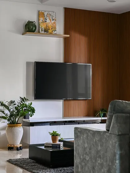 This TV unit combines a wooden fluted back panel with a sleek white console. The design creates a beautiful contrast of texture and color, with the fluted panel extending across the wall for a seamless look.