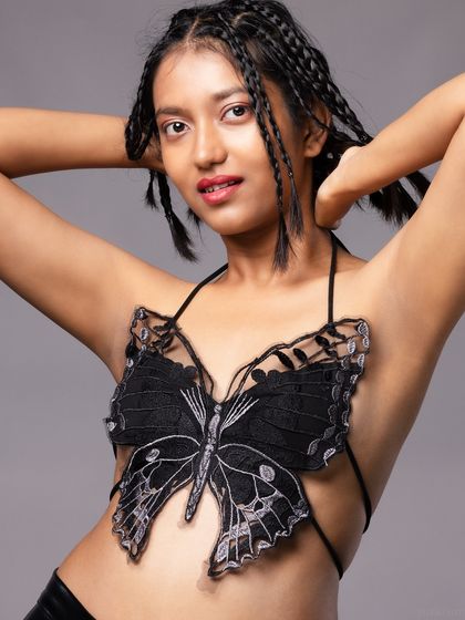 A creative portrait featuring a model with braided hair wearing a delicate butterfly-shaped top. This look is perfect for a whimsical or conceptual fashion story.