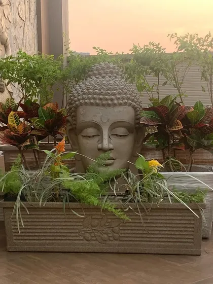 A key element of my styling is creating a sense of peace, often through Zen-inspired decor. This planter, featuring a serene Buddha head surrounded by colorful crotons and other foliage, instantly becomes a tranquil focal point on a terrace.