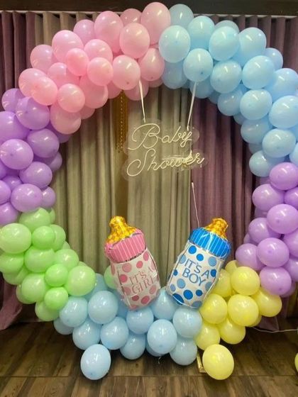 A colorful pastel rainbow baby shower ring, with "It's a Boy" and "It's a Girl" baby bottle foil balloons.