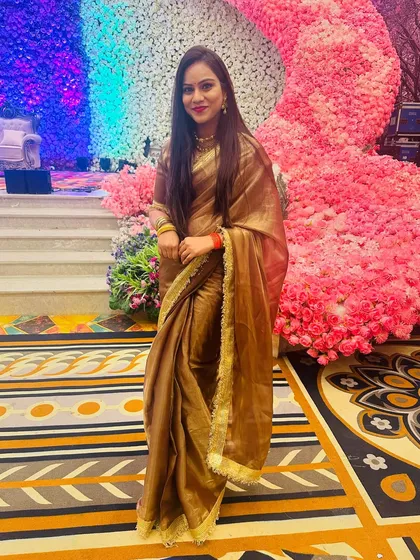 A full-length shot of the client in her brown and gold tissue saree, showcasing its beautiful drape and shine.