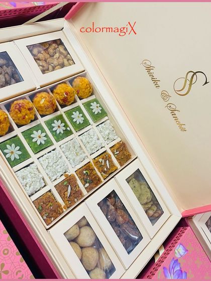 A detailed look inside our personalized pink wedding hamper, revealing a colorful array of motichoor laddoos, pista barfi, and other traditional Indian sweets.