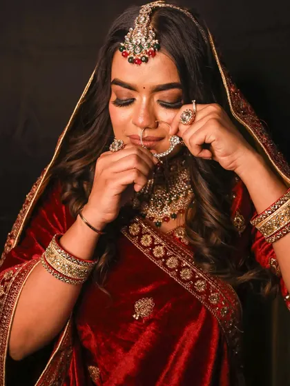 A candid moment of the bride adjusting her nath, showing the intricate details of the jewellery and her henna.