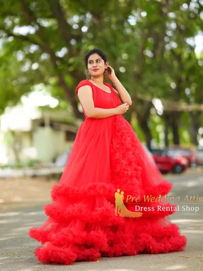 A lovely portrait in our red ruffled gown, showcasing its flattering fit and voluminous skirt. This dress is perfect for capturing the joy and beauty of pregnancy in an outdoor setting.