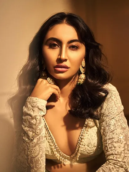 A close-up showcasing the soft glam look on Khatija Iqbal. The focus is on flawless skin, a subtle pink lip, and beautifully defined eyes, complemented by statement gold earrings.