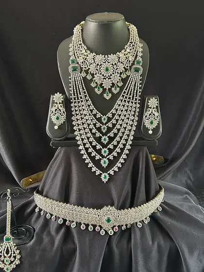 Make a statement with this breathtaking silver-toned bridal set, studded with high-quality white and green stones. The multi-layered necklace and grand choker are designed to give you a dazzling look for your reception or engagement. This set is a fantastic rental option for a modern yet regal appearance.