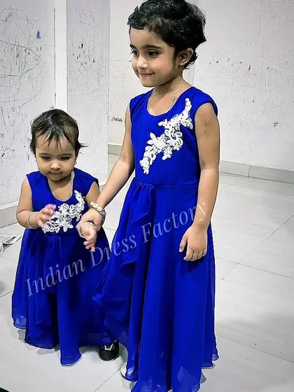 Twinning is winning, especially for sisters. I designed these matching royal blue georgette gowns for two sisters. The design features an elegant asymmetrical hemline and delicate white floral appliqué, creating a stylish and coordinated look for a special occasion.