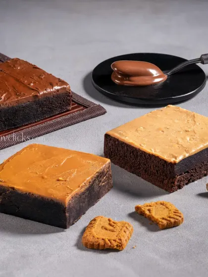 Slices of Biscoff and Nutella brownies, styled with their respective spreads to clearly communicate the flavors.