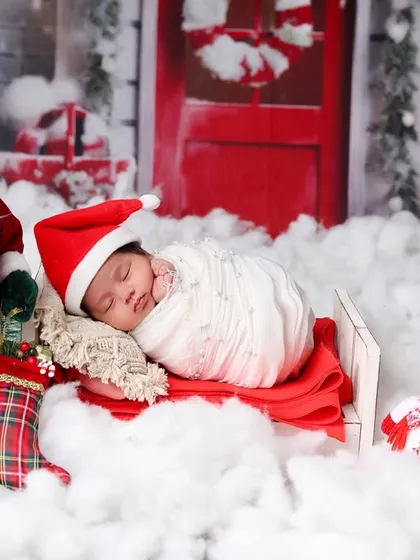 A classic Christmas scene with a sleeping newborn, Santa Claus, a snowman, and a festive red door in the background.