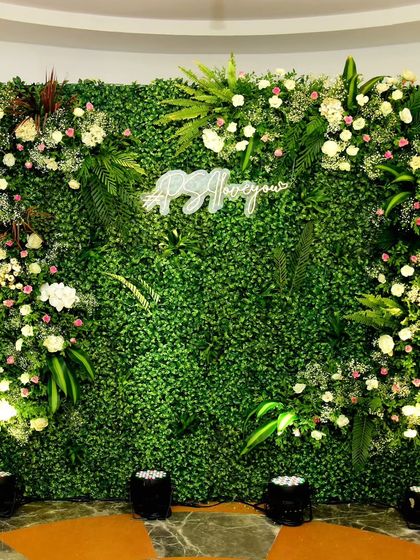 A lush green wall serves as a perfect, natural backdrop for a custom neon sign. This one, featuring the couple's hashtag, became a popular photo spot.