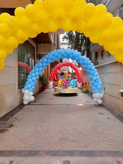 A vibrant balloon archway in primary colors creates a tunnel-like entrance for the Peppaland party, leading guests to a mini carousel for an extra touch of fun.