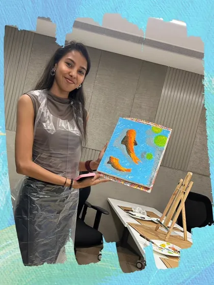 A participant proudly holds up her finished koi fish painting, a great example of what you can create in just one session.