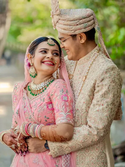 A picture of happiness. This couple glows in their pastel pink and ivory outfits, with the bride's soft makeup adding to the romance.