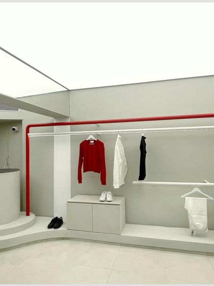 The minimalist apparel display system uses simple white rods and a neutral backdrop. This ensures the clothing is the hero, allowing for easy browsing and a clean aesthetic.