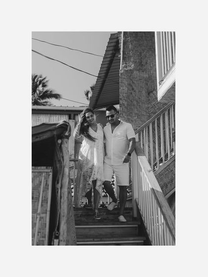 A candid black and white shot of the couple walking down the stairs of a beach shack. It captures a simple, happy moment in a classic, timeless style.