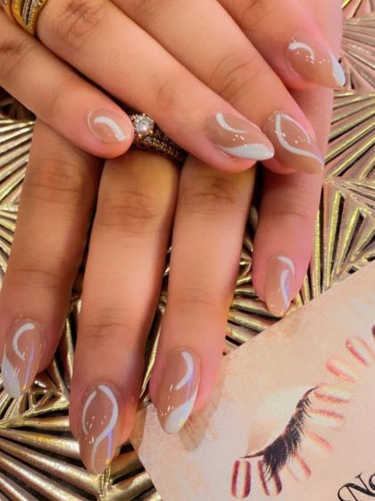 An elegant abstract design on almond-shaped nails. The nude base is decorated with delicate white and grey swirls for a soft, modern look.