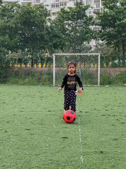 Taking her first steps in football. This young player stands confidently with her ball, ready to learn and play.