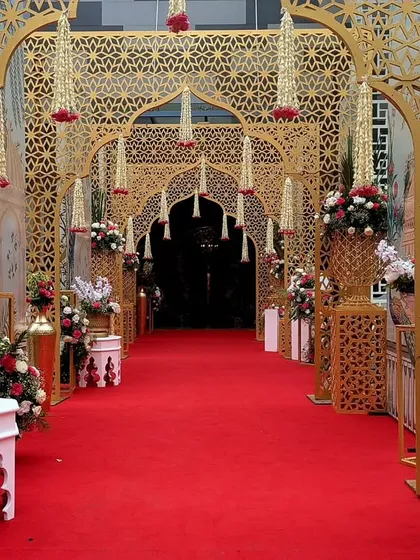 I love to create entrances that transport you. For this wedding, I designed a series of intricate golden arches with hanging floral strings, leading guests down a regal red carpet into a modern-day palace.