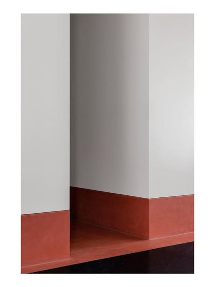 This abstract detail highlights the high skirting made from a terracotta-hued material, which runs along the periphery of the main living areas. It's a continuous line that ties the different spaces together.