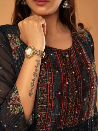 A detail shot for a brand, focusing on the embroidered sleeve and the model's tattoo.