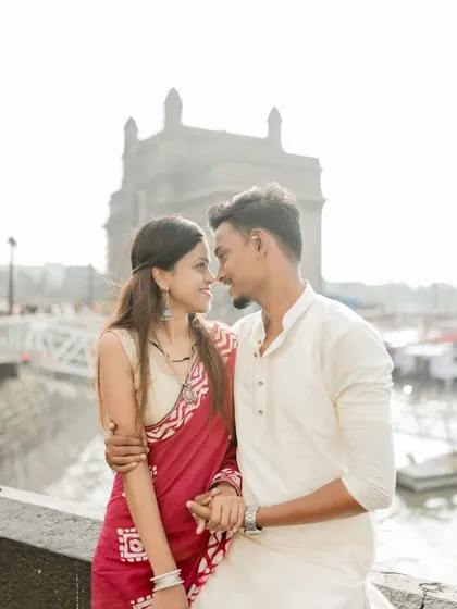 An intimate couple portrait captured at the Gateway of India, with the bride in a beautiful red saree and the groom in a classic white kurta. This image celebrates love rooted in Maharashtrian tradition against a landmark Mumbai backdrop.