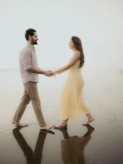 Walking hand-in-hand, reflected in the tide. This shot captures the simple romance of a pre-wedding stroll on the beach.