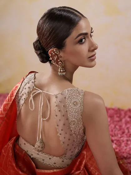 A modern take on the bridal blouse, featuring a sheer back with scattered beadwork and an elegant tie-up tassel. This design offers a contemporary feel while maintaining traditional craftsmanship.