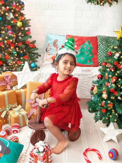 This little girl is all smiles in her festive red dress, ready for Christmas. The holiday props and cheerful setup make these sessions so much fun.