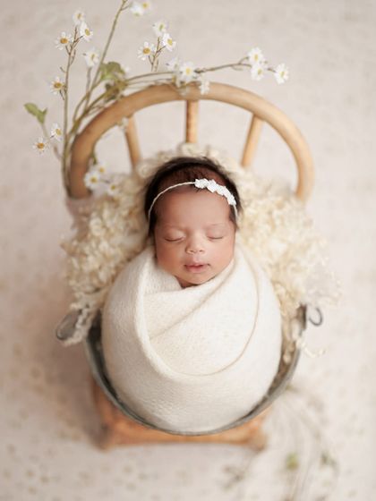 Like a delicate daisy. This all-white setup with tiny flowers is so pure and serene. The baby is wrapped snugly in a bucket chair, looking like a little angel.
