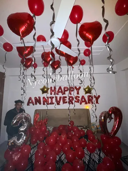 This is my classic anniversary room decoration service. The setup includes red 'HAPPY ANNIVERSARY' foil letters, dozens of red balloons covering the bed and ceiling, and a large number balloon to mark the special year, like this third anniversary celebration.