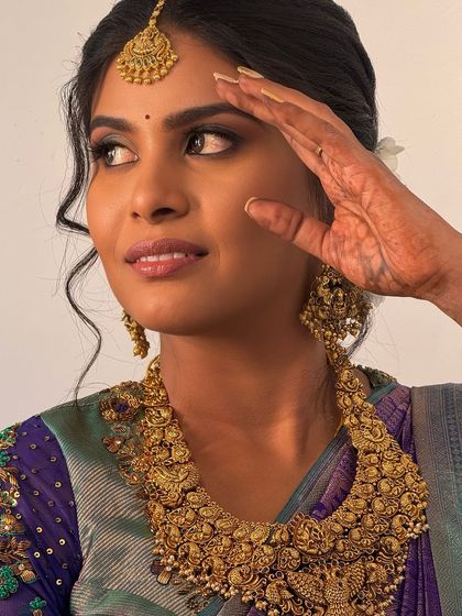 A close-up, artistic shot of Abi, highlighting her bold makeup and the intricate details of the antique necklace.