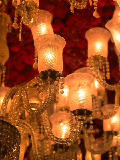 A close up of the vintage style crystal chandelier. The intricate details of the glass and the warm light it casts were essential in creating the sophisticated, old world charm of this reception.