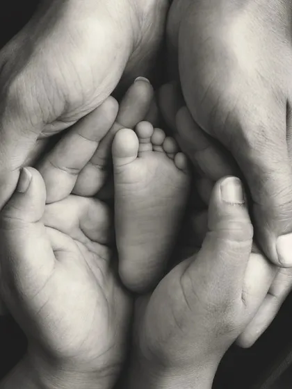 Sometimes, the biggest love is found in the tiniest details. This classic black and white photo focuses on a newborn's perfect little foot held safely in their parents' hands, a timeless symbol of protection, love, and a new beginning.