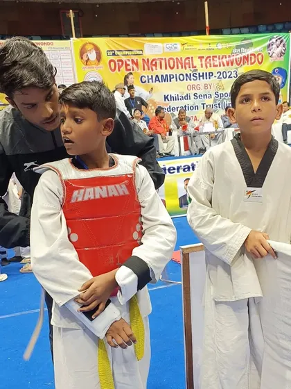 An older student helps a younger one get ready for his match, showing our team spirit.