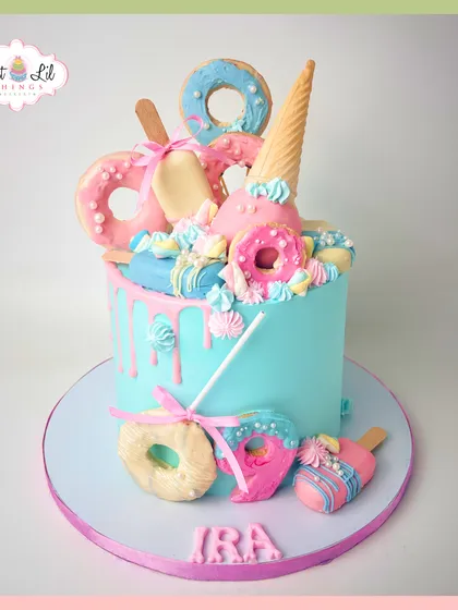 A pastel party on a cake! This drip cake for Ira is topped with donuts, ice cream cones, and popsicles in a dreamy blue and pink color scheme.