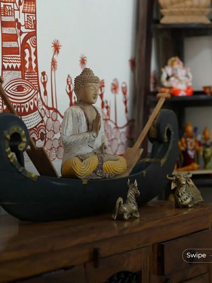 A decorative corner featuring a Buddha statue in a boat, along with other small brass idols. These details infuse the space with spirituality and traditional craftsmanship.