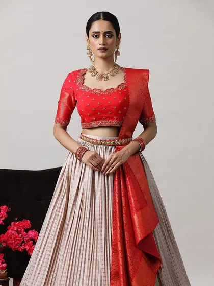 Another view of the red and beige lehenga, highlighting the intricate details of the blouse and the rich Banarasi border.