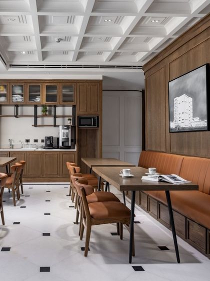 The cafeteria at the VRS Office provides a refined space for employees to relax and recharge. It features classic wood-panelled walls, a coffered ceiling, and comfortable leather-upholstered seating, continuing the office's blend of luxury and formality.