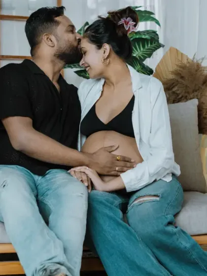 A tender moment between the expecting couple. The gentle kiss and shared smile make this a heartwarming portrait from their boho studio session.