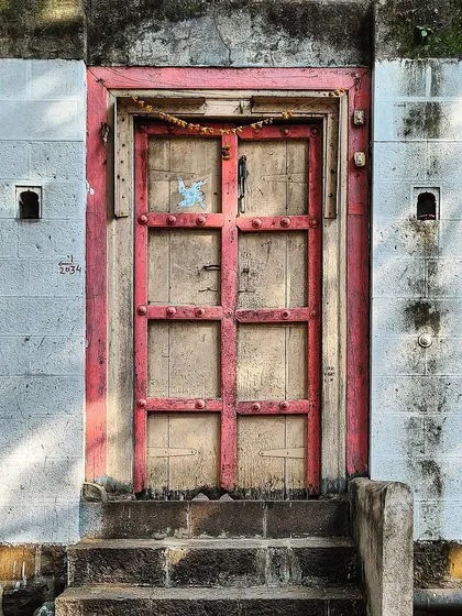 This old wooden door with a pink frame is set into a stark white wall. The contrast in colors and textures, along with the worn steps, makes for a compelling architectural portrait.