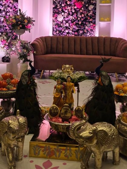 A beautiful centerpiece for an engagement, with dolls representing the couple, surrounded by peacock figures and silver elephant props.