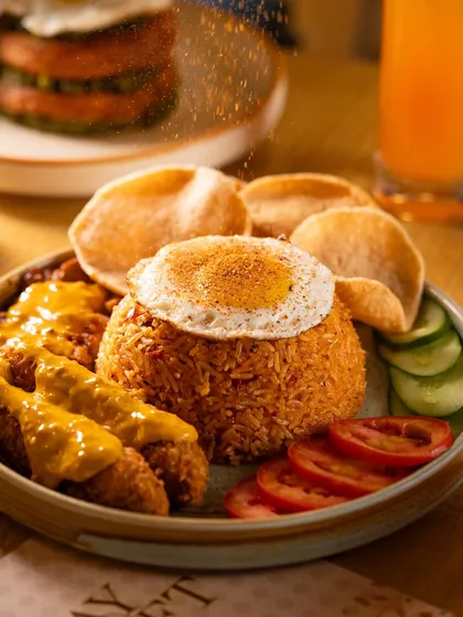 A close-up of seasoning being sprinkled over fried rice, capturing the individual grains of spice.