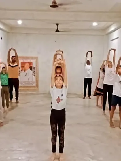 Students practicing Tadasana (Mountain Pose) with arms stretched up. This simple pose helps improve posture and body awareness.