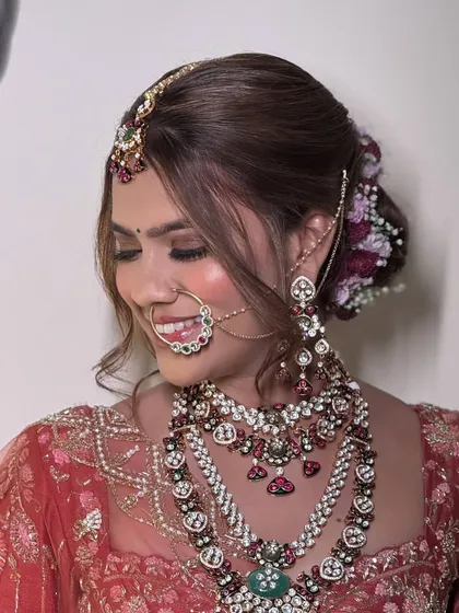 A happy bride smiling, adorned in a multi-layered kundan and polki set. The intricate details and colorful stones make this a truly special piece for a once-in-a-lifetime day.