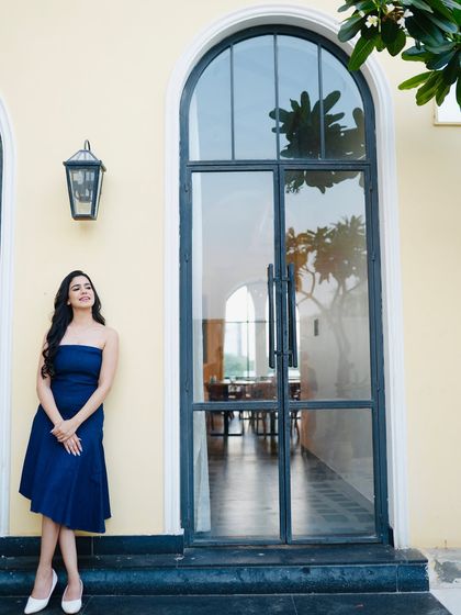 A full-length shot of the blue dress against a beautiful arched window, perfect for a lifestyle or fashion blog feature.
