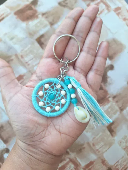 This turquoise dreamcatcher keychain features a real shell and a matching tassel, bringing beachy, bohemian style to your keys.