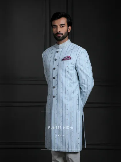An achkan that feels like a sonnet in ice blue. Pintucks and embroidery give it rhythm, sequins lend it sparkle, and a vintage touch seals it with nostalgia.