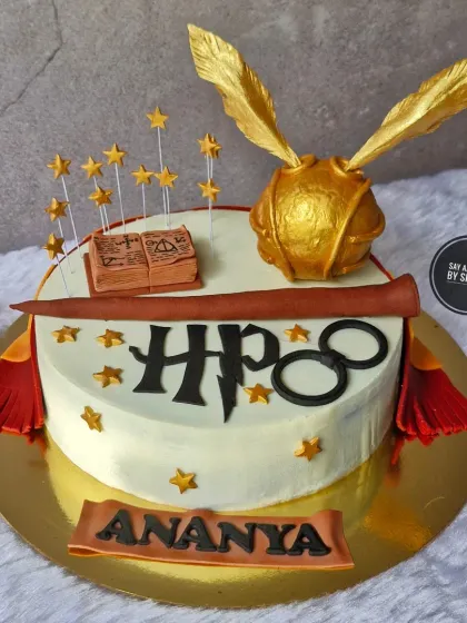 A magical cake for a Harry Potter fan. This design includes iconic, handmade elements from the Wizarding World, such as the Golden Snitch, a spellbook, and Harry's glasses, all completely edible.
