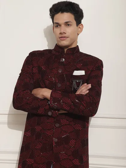 A closer look at the deep red Indo-Western jacket, showcasing its unique pattern and the stylish brooch detail. It's a look that is confident and modern.