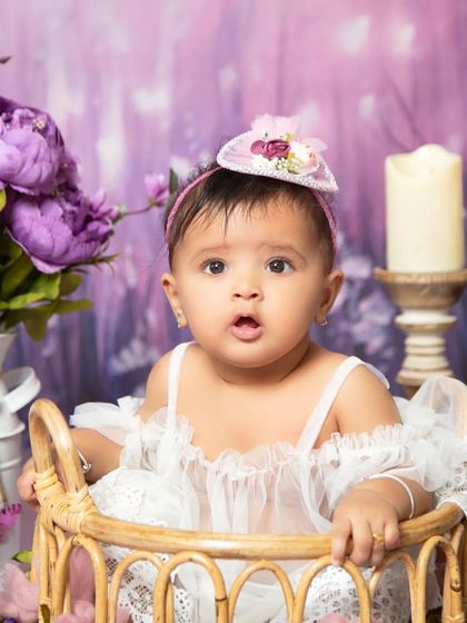 A close-up portrait from the purple floral session, highlighting the baby's sweet expression and the delicate details of her outfit.